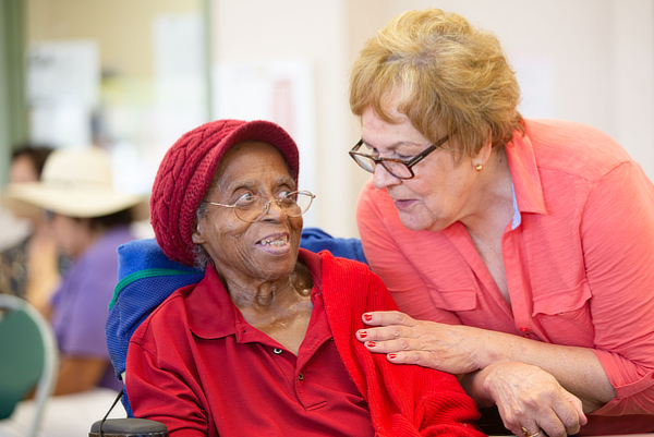 Hispanic and  African American women together in a busy senior center